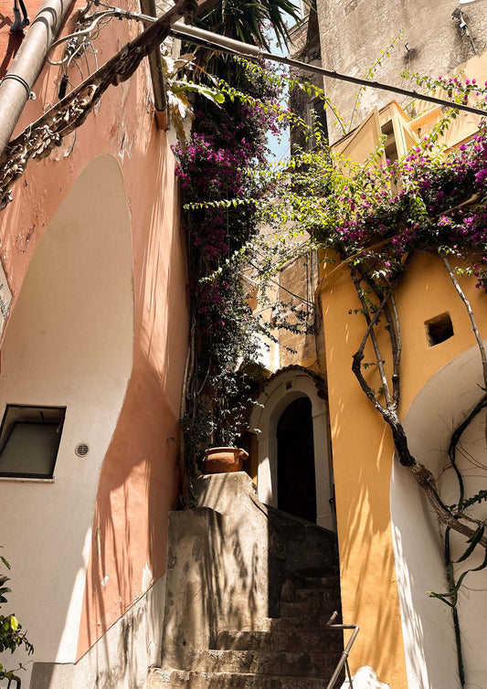 Fine art print titled “Le Strade di Positano,” featuring a sunlit alleyway winding through pastel buildings and bougainvillea in the heart of the Amalfi Coast. This image captures the charm and vibrancy of southern Italy—ideal for coastal, Mediterranean, or wanderlust-inspired interiors.