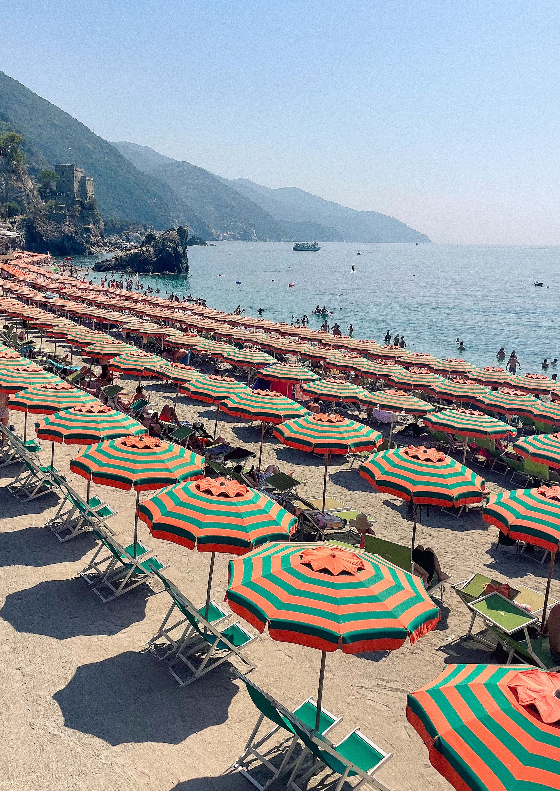 Fine art print titled “Ombrelloni di Fegina,” featuring a striking aerial view of colourful beach umbrellas lined up along the sandy shore of Monterosso al Mare in Cinque Terre. This vibrant image captures the playful charm of Italian summers—perfect for coastal, retro, or Mediterranean-themed interiors.