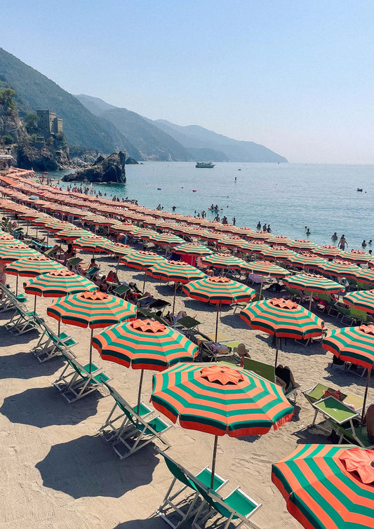 Fine art print titled “Ombrelloni di Fegina,” featuring a striking aerial view of colourful beach umbrellas lined up along the sandy shore of Monterosso al Mare in Cinque Terre. This vibrant image captures the playful charm of Italian summers—perfect for coastal, retro, or Mediterranean-themed interiors.